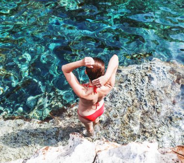 Kırmızı bikinili bir kızın bir t karşı bir uçurumun kenarında duruyor