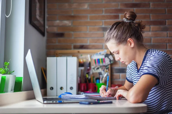 Девушка студентка фрилансер, работающая с ноутбуком на дому Windo — стоковое фото