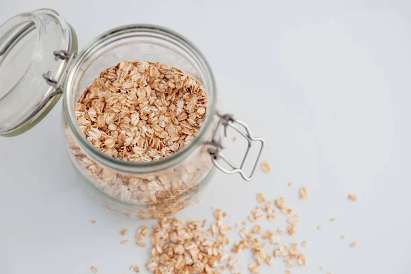 Harina de avena en un frasco de vidrio sobre un fondo blanco, alimentación saludable — Foto de Stock