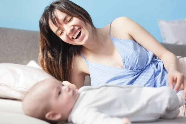 Schöne junge glückliche Frau mit ihrem neugeborenen Baby liegt auf der — Stockfoto