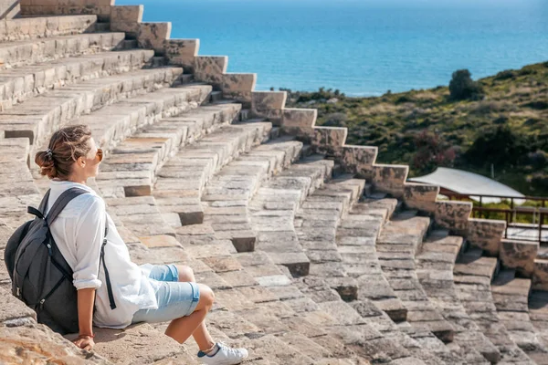 Uma jovem mulher bonita viajante senta-se nos degraus de um amphith — Fotografia de Stock