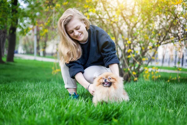 Schattige tiener meisje met blond haar spelen met haar Pommeren puppy — Stockfoto