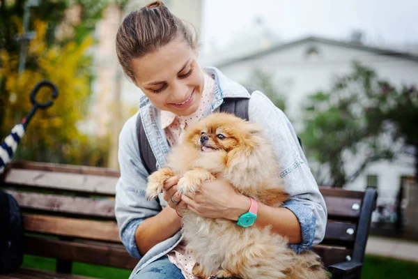 Mulher bonita com seu cachorro da Pomerânia em suas mãos em — Fotografia de Stock