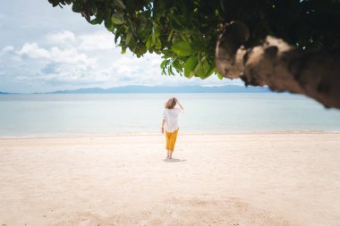 Beyaz gömlekli ve sarı pantolonlu güzel bir kadın yürür