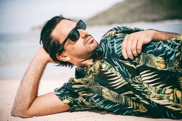 Elegante joven morena sexy hombre con una barba en una camisa hawaiana — Foto de Stock