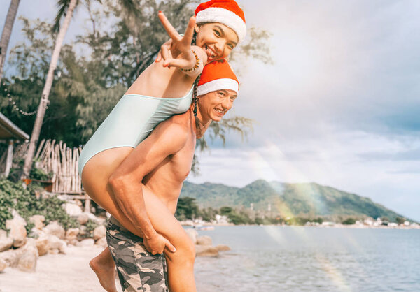 Christmas happy couple portrait, beach vacation. Mixed race Asia