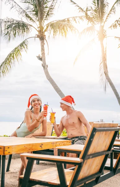Noel Baba şapkalı mutlu genç çift bunu kutluyor. — Stok fotoğraf