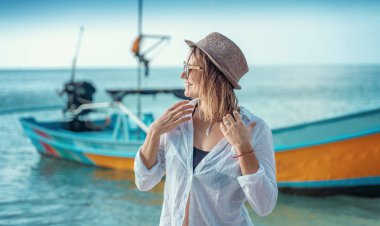 Beyaz gömlekli ve güneş gözlüklü güzel bir kadın v 'nin tadını çıkarıyor.