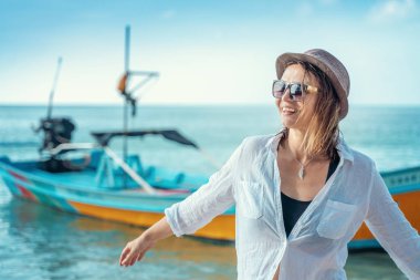 Beyaz gömlekli ve güneş gözlüklü güzel bir kadın v 'nin tadını çıkarıyor.