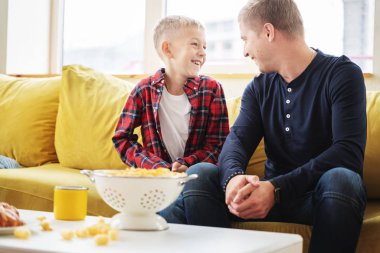 Mutlu genç baba ve oğul 8 yaşında neşeyle sohbet ediyorlar. 