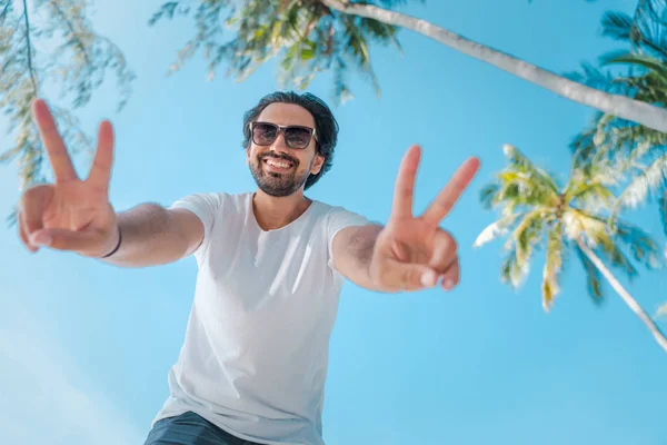 Jeune homme latin beau dans un t-shirt blanc et des lunettes de soleil sur un — Photo