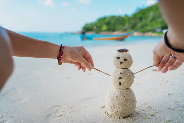 Nő épít egy hóembert a homokból a tengerparton a háttérben — Stock Fotó