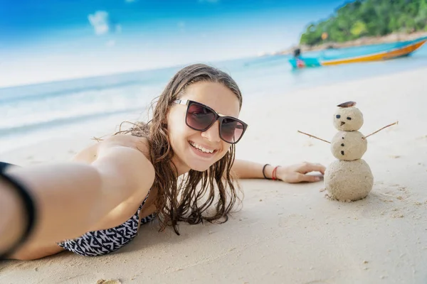 Joven hermosa mujer toma una selfie al lado de un muñeco de nieve hecho de s —  Fotos de Stock