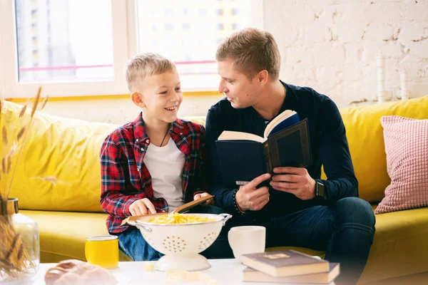 Junger glücklicher Vater mit Sohn Junge 8 Jahre alt, der Bücher auf einem y liest — Stockfoto