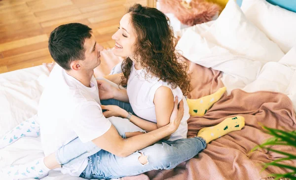Ευτυχισμένο νεαρό ζευγάρι αγκαλιάζει τρυφερά στο κρεβάτι στην κρεβατοκάμαρα, r — Φωτογραφία Αρχείου