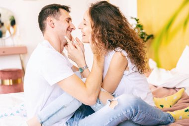 Mutlu genç çift yatak odasındaki yatakta şefkatle sarılıyorlar.