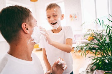 Yüzlerinde tıraş köpüğü olan bir adam ve küçük bir çocuk...