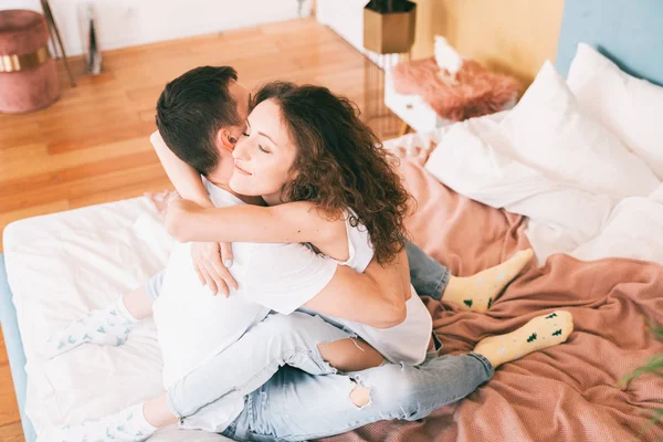 Ευτυχισμένο νεαρό ζευγάρι αγκαλιάζει τρυφερά στο κρεβάτι στην κρεβατοκάμαρα, r — Φωτογραφία Αρχείου