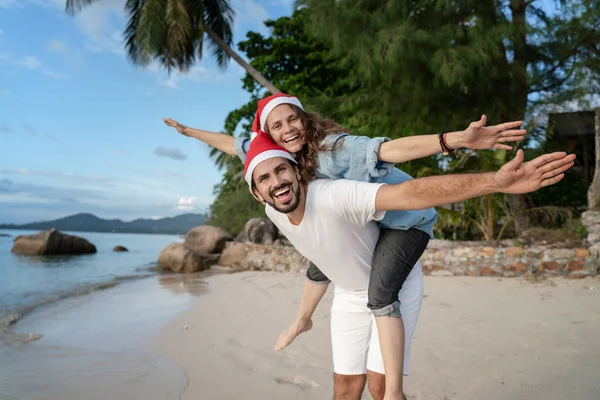 Jeune beau couple dans le Père Noël chapeaux promenades le long de la côte — Photo