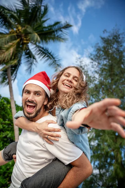 Jeune beau couple dans le Père Noël chapeaux promenades le long de la côte — Photo