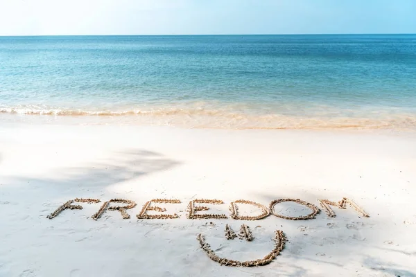 在热带海滩的沙滩上写下的自由这个词是最生动的 — 图库照片