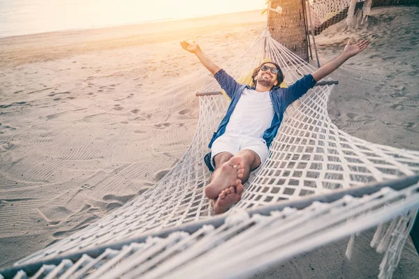 Jovem relaxando na rede na praia. Felicidade, liberdade de va — Fotografia de Stock