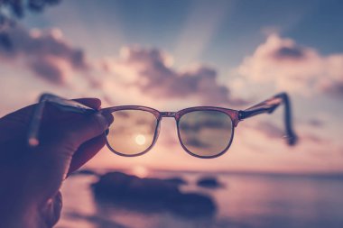 Denizde gün batımını gören güneş gözlükleri. Boşalt