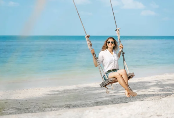 Hermosa chica rizada divertida joven en un columpio en una playa tropical , —  Fotos de Stock