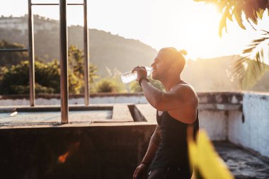 Yakışıklı genç Avrupalı adam, elektrik tesisatından sonra su içiyor.