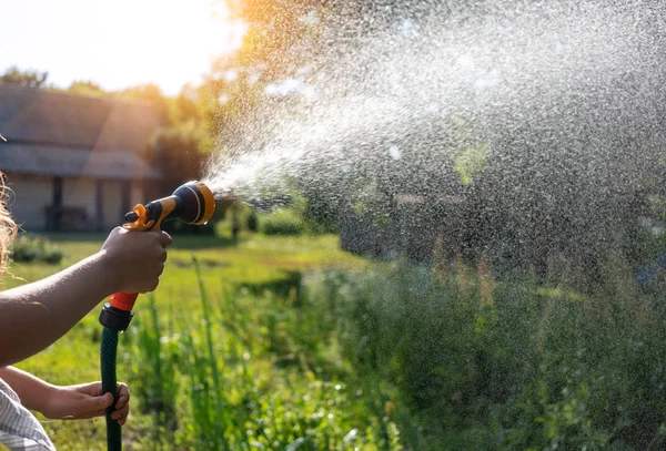 Drinkinstallaties tuin apparatuur - hand houdt de sprinkler slang voor ir — Stockfoto