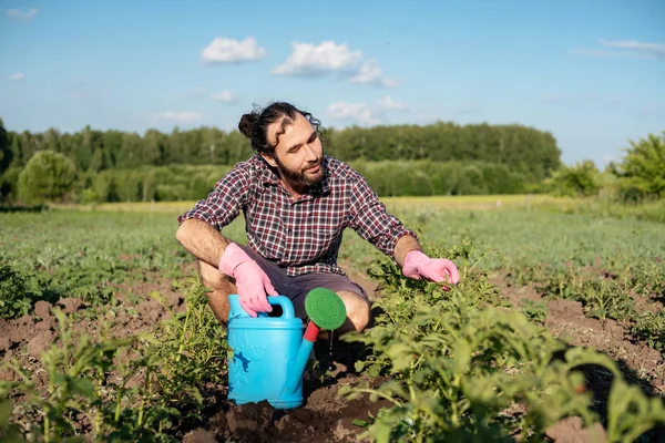Joven hombre guapo cultiva plantas en su jardín, cuida pla —  Fotos de Stock