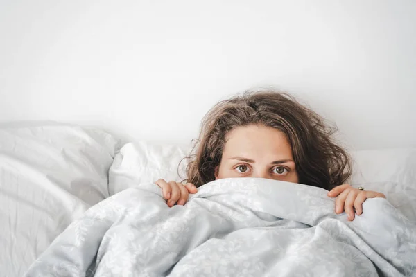 Beautiful Young Curly Woman Lies Bed Looks Out Covers Looking — Stock Photo, Image