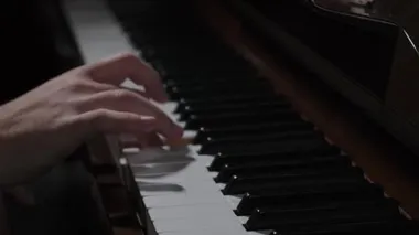 Erkek eller karanlıkta piyano çalıyor.