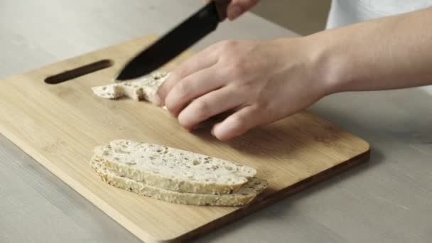 女性の手は木製の黒板にゴマと白パンを切断 — ストック動画