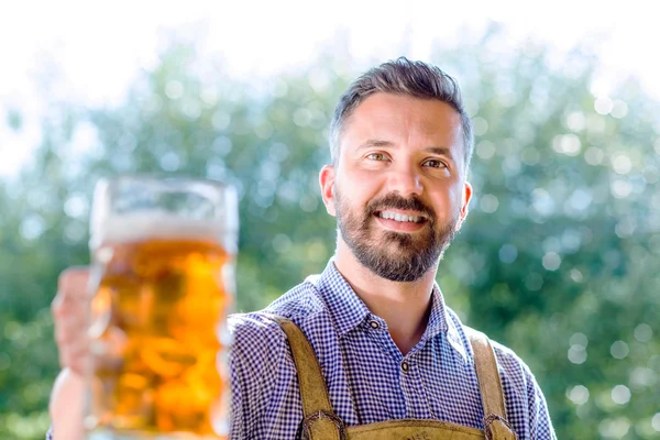 Человек в баварской одежде держит пиво — стоковое фото