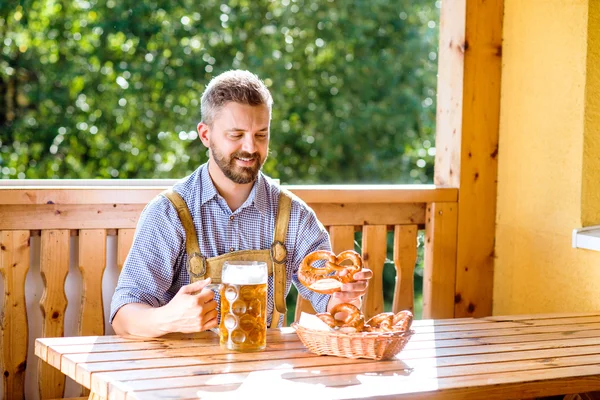 Man in bavarian clothes with beer and pretzels — Stock Photo, Image