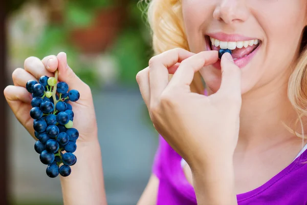 Jonge vrouw blauwe druiven eten — Stockfoto