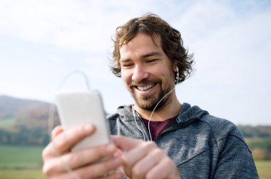 Akıllı telefon ve kulaklık ile genç atlet 