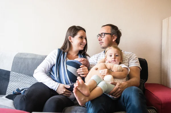 Junge Eltern mit Kindern auf dem Sofa — Stockfoto