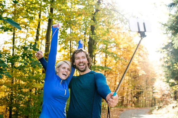 Hermosos corredores en el bosque de otoño tomando selfie con teléfono inteligente —  Fotos de Stock