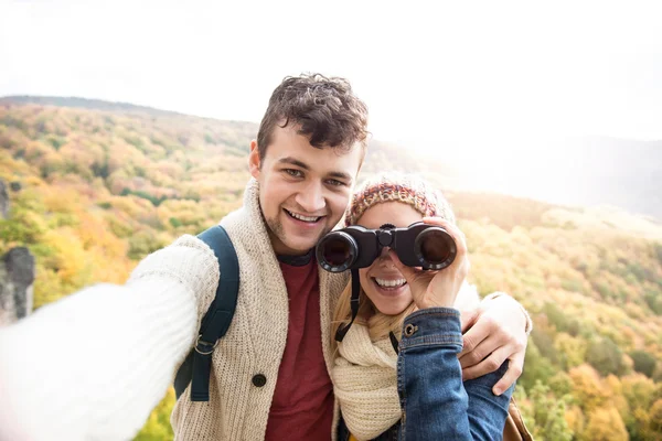 Unga par på en promenad i höst skog tar selfie — Stockfoto