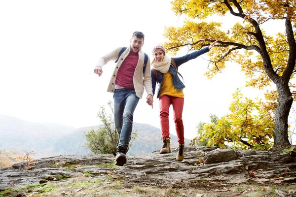 Beau couple dans la nature ensoleillée d'automne, courant sur un rocher — Photo