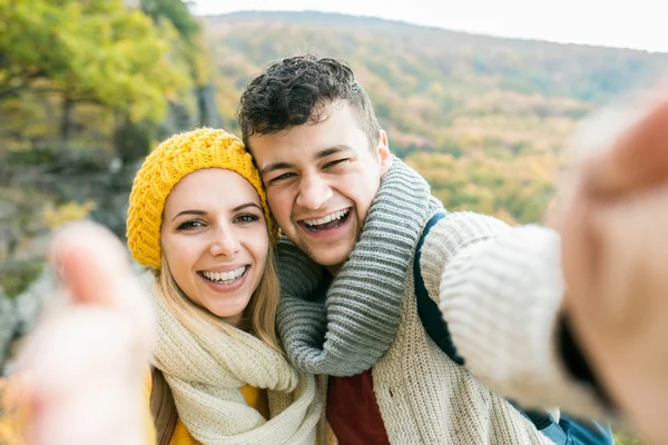 Unga par på en promenad i höst skog tar selfie — Stockfoto