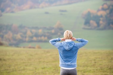 Güneşli doğada dışında sarışın runner germe. Arkadan görünüş.