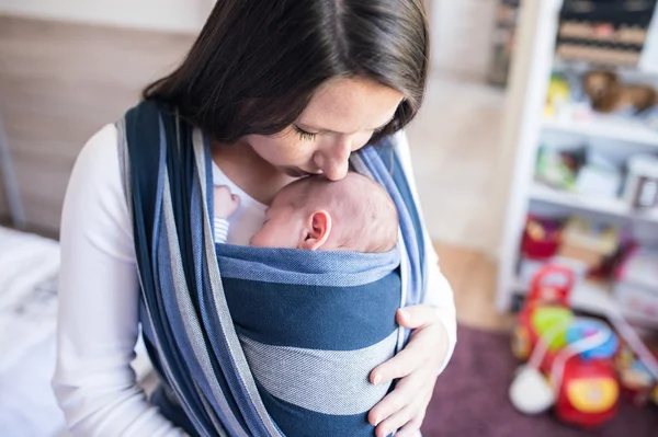 Schöne junge Mutter mit ihrem Sohn im Tragetuch — Stockfoto