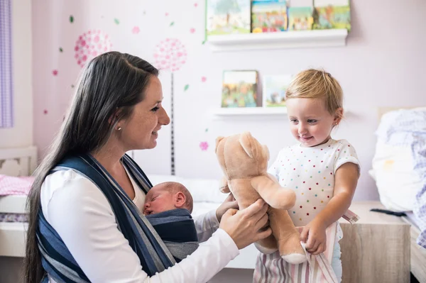 Madre con hijo en honda e hija con oso de peluche — Foto de Stock