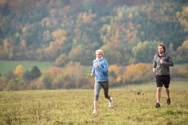 Beau jeune couple courant dans la nature ensoleillée d'automne . — Photo