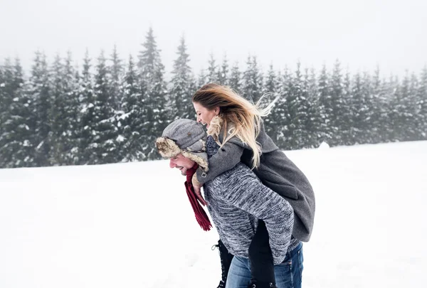 Homem dando mulher piggyback no inverno — Fotografia de Stock