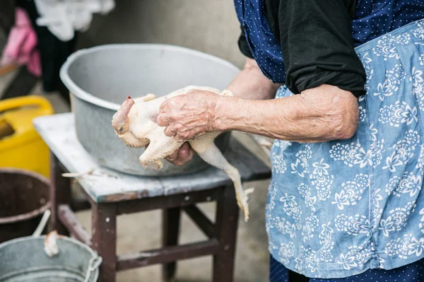 Mulher sênior limpeza frango abatido — Fotografia de Stock