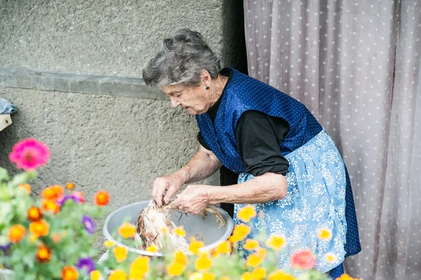 Senior vrouw schoonmaak kip. — Stockfoto